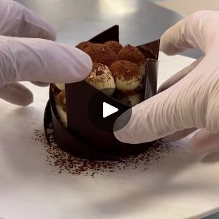 two hands in white gloves are placing pastries into a box