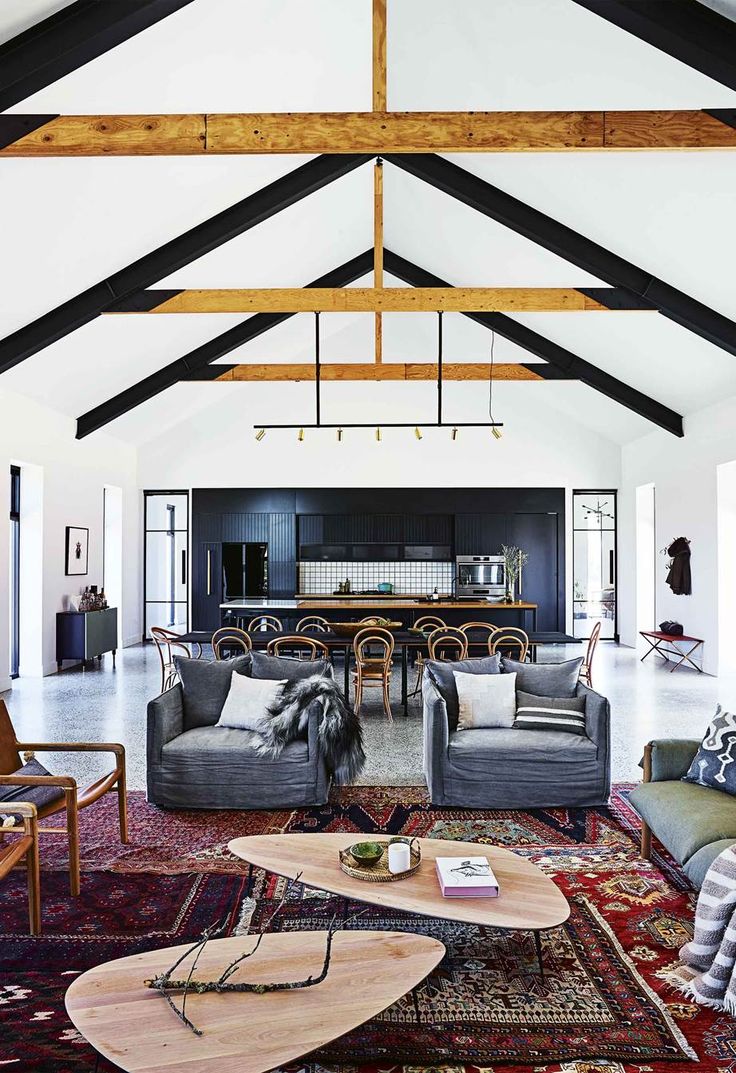 a living room filled with furniture and a wooden beam ceiling over an area rug that has been placed on the floor