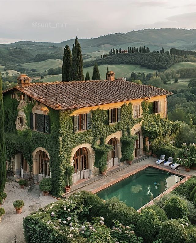 an aerial view of a house with a pool surrounded by greenery and trees in the foreground