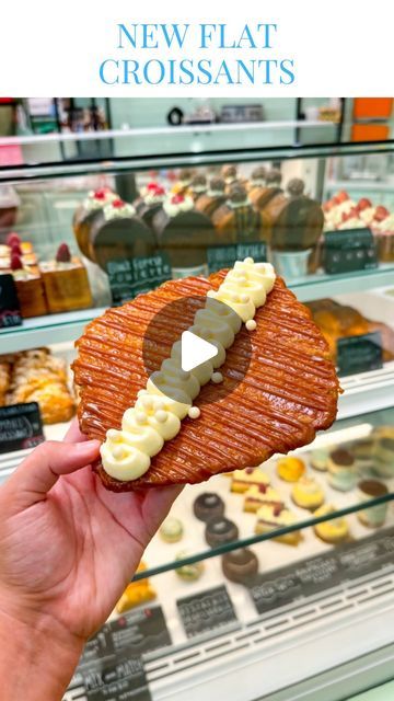 a person holding up a pastry in front of a display case