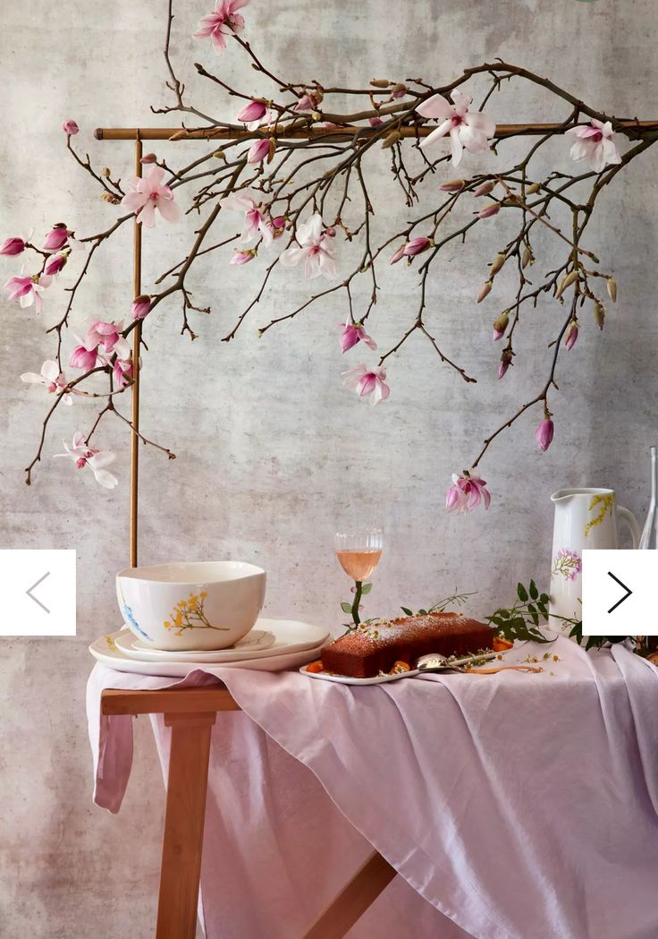 a table topped with a bowl and plate next to a tree branch