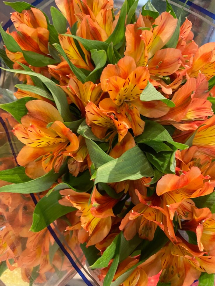 an arrangement of orange flowers in a glass vase