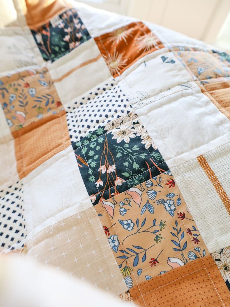 a close up of a patchwork quilt on a bed with blue and orange flowers