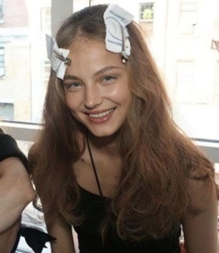 two young women sitting next to each other in front of a window smiling at the camera