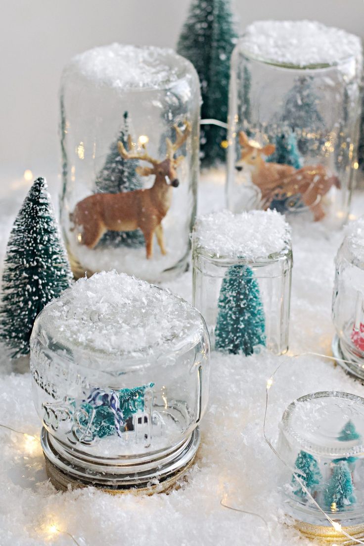 several glass jars filled with snow and christmas decorations