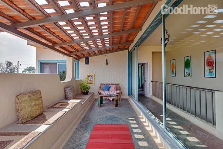 an outdoor covered patio area with red rugs on the floor and wooden slatted roof