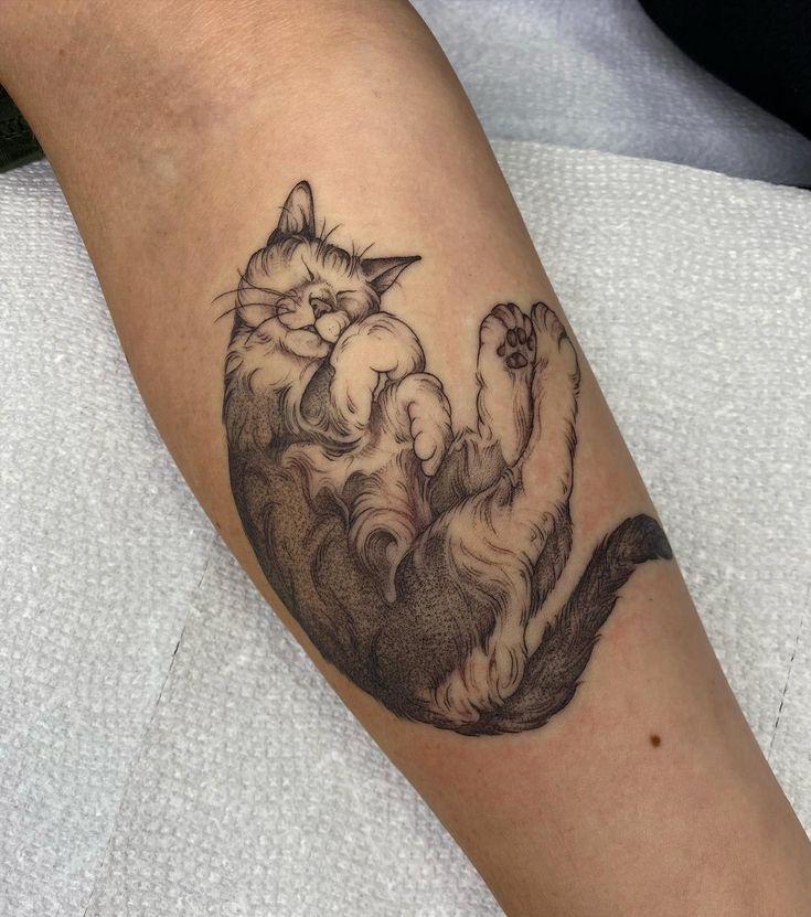 a black and white cat tattoo on the arm