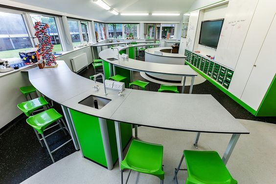 an empty classroom with green chairs and desks