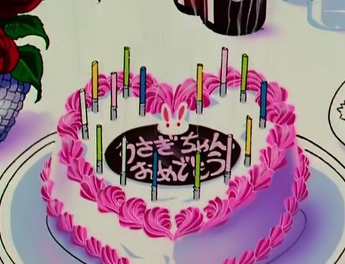 a cake with pink frosting and candles in the shape of a heart on a plate