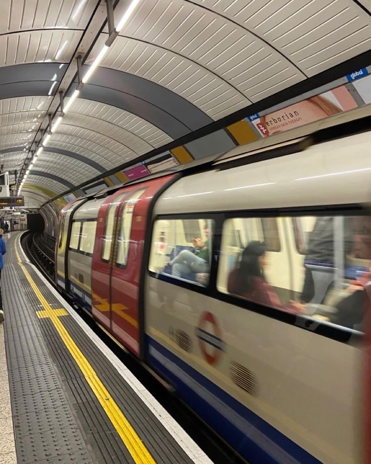 a train traveling through a subway station next to people