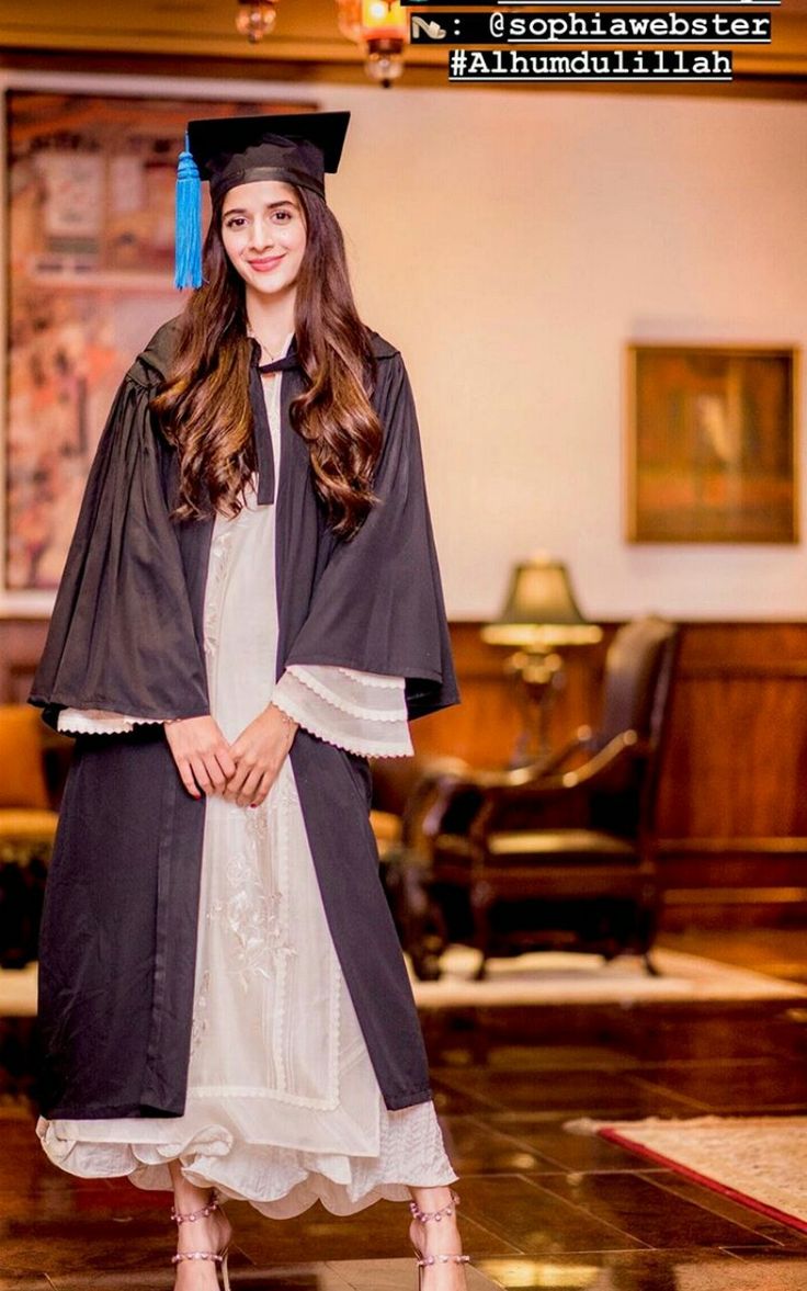 a woman in a graduation gown and cap posing for the camera with her hand on her hip