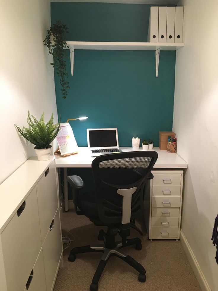 an office with a desk, chair and computer on top of the desk in front of a green wall