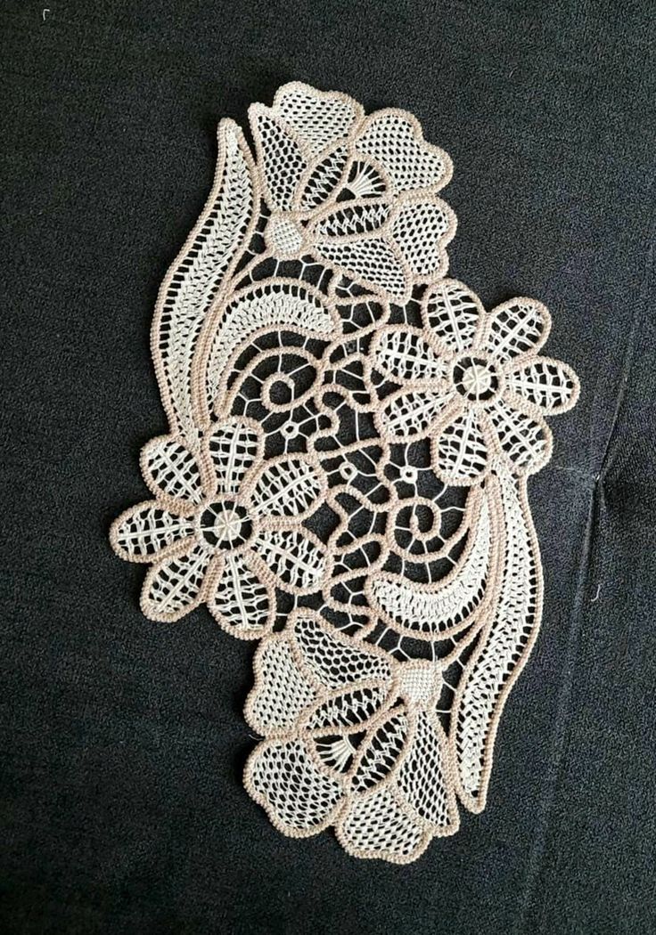 an embroidered doily is shown on a black shirt with white flowers and leaves in the center