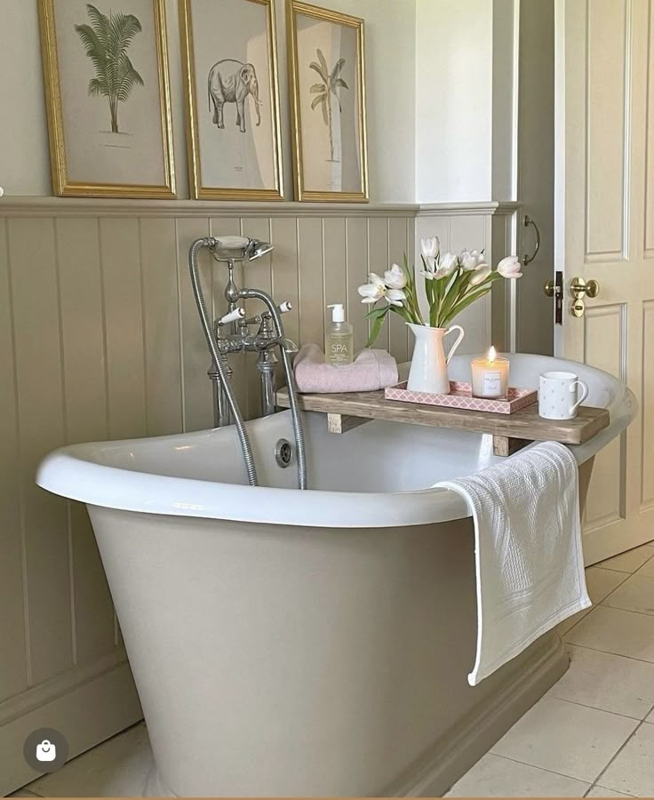 a white bath tub sitting in a bathroom next to two framed pictures on the wall