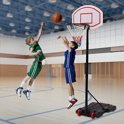 two young boys are playing basketball in an indoor gym, one is jumping up to the basket