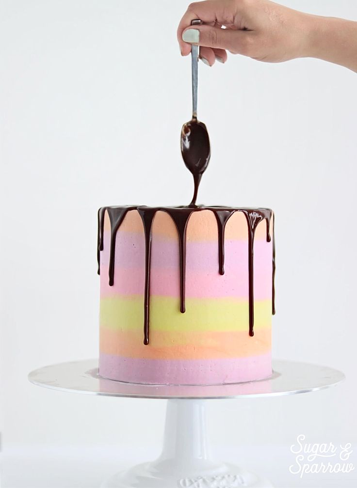 a cake with chocolate drizzled on top is being held by a person