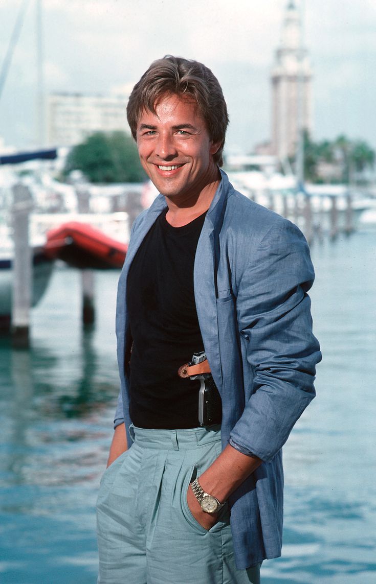 a man standing next to the water with his hands in his pockets and smiling at the camera