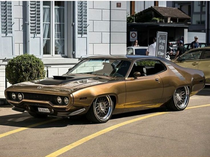 a gold muscle car parked in front of a building