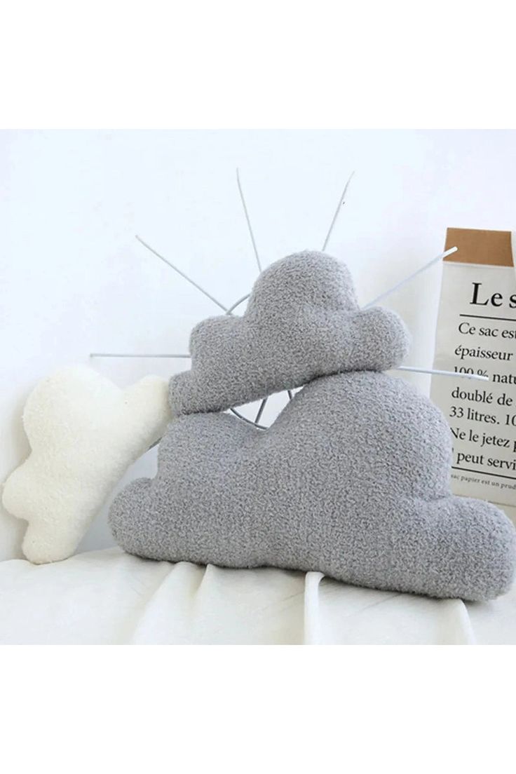 a cloud pillow sitting on top of a bed next to a piece of paper that says less sleep