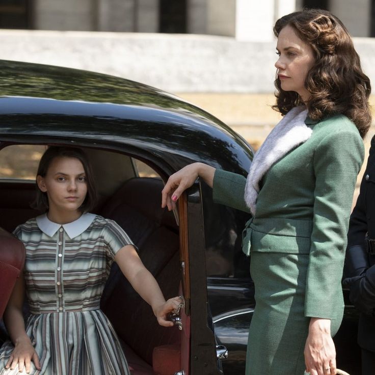 a woman standing in the back of a car next to another woman