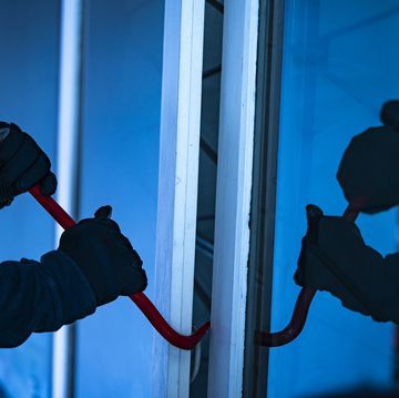 a man is working on the side of a window with a red cord attached to it