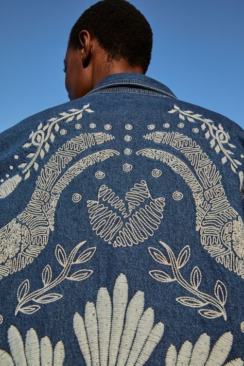 a man wearing a blue jacket with white designs on it and his back turned to the camera