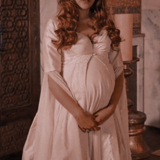 a pregnant woman wearing a white gown and tiara