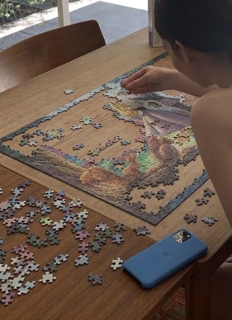 a young boy sitting at a wooden table with a puzzle on it's floor