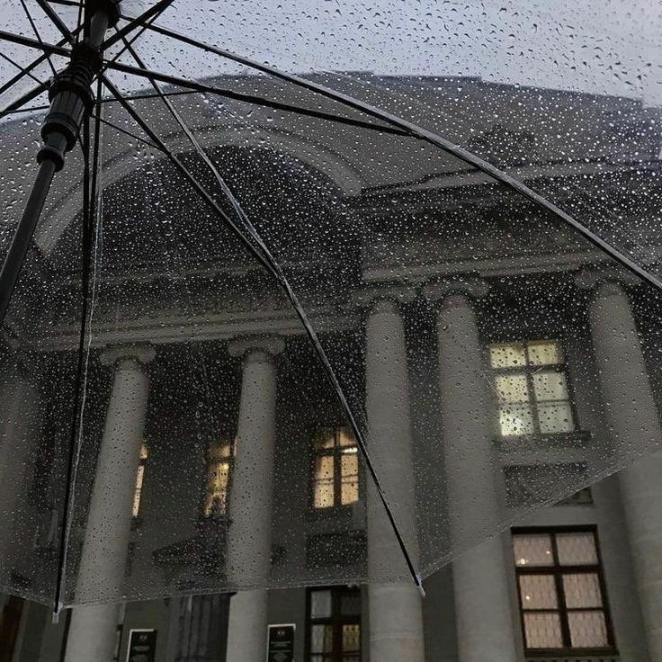 an open umbrella in front of a building with columns and windows on it's side