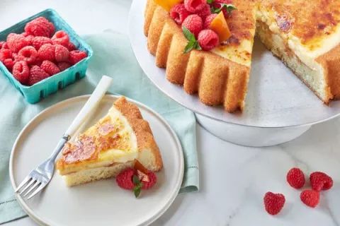 a cake on a plate with raspberries and oranges next to the cake