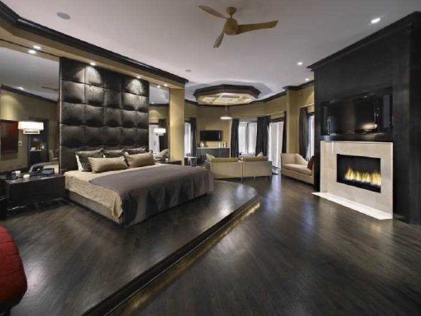 a large bedroom with black walls and wooden floors, along with a fireplace in the center