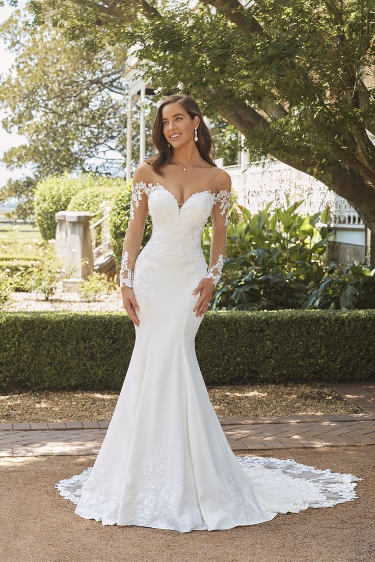 a woman in a white wedding dress posing for the camera with her hands on her hips