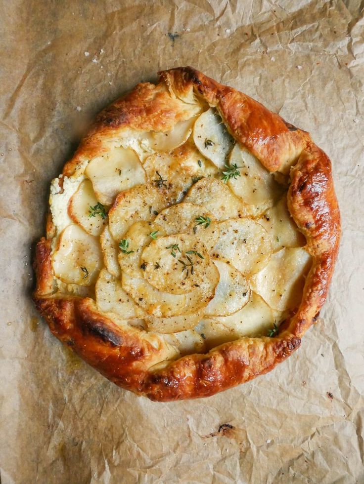 a pizza sitting on top of a piece of wax paper covered in cheese and herbs