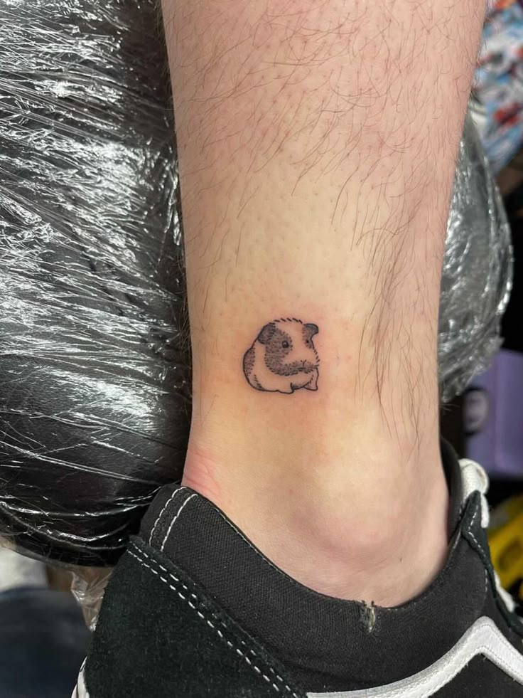 a small panda bear tattoo on the side of someone's leg, with one paw resting on his head