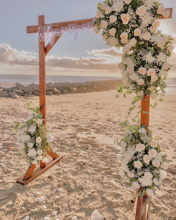 an arch decorated with flowers on the beach