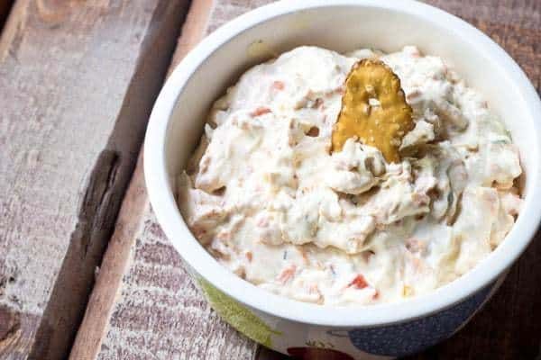 a bowl filled with some kind of food on top of a wooden table next to a spoon