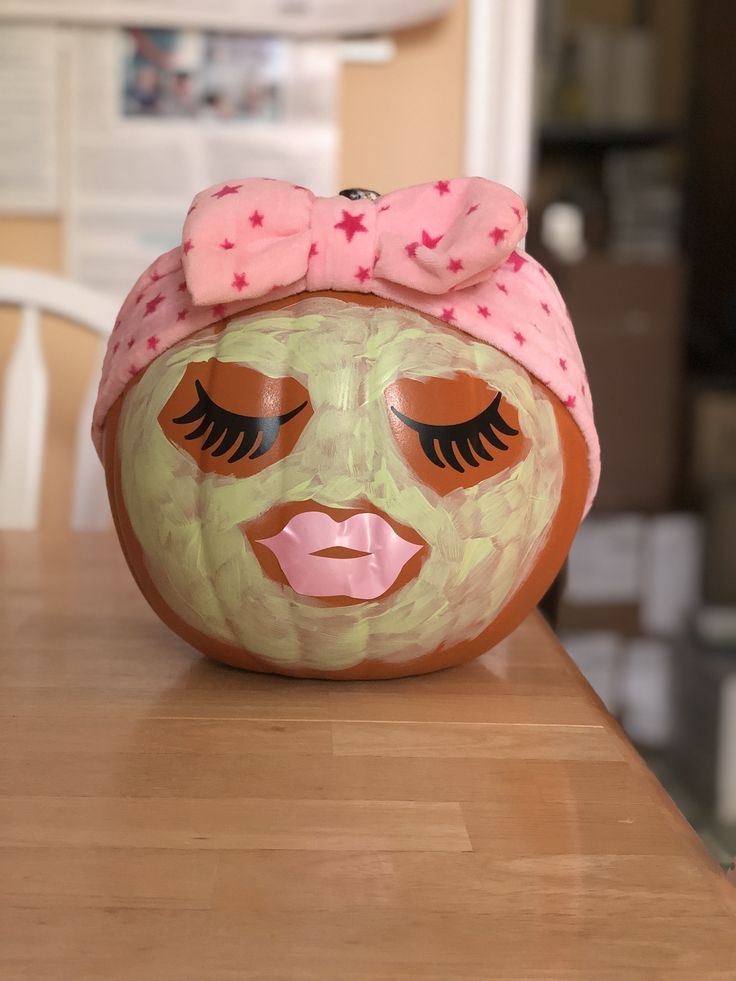 a ceramic pumpkin with a pink bow on it's head sitting on a table