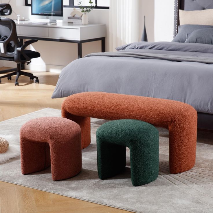 two stools sitting on the floor in front of a bed with a gray comforter