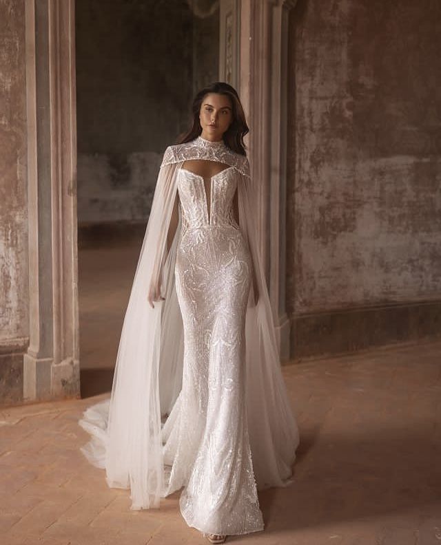 a woman in a white wedding dress with a veil on her head and long sleeves