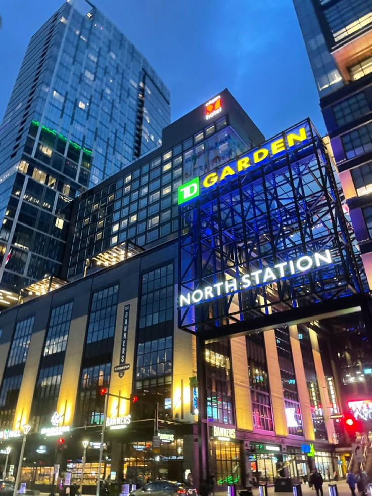 a city street at night with tall buildings and neon lights on the side of it