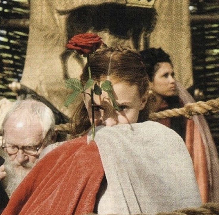 a woman with a rose in her hair standing next to other people and looking at something