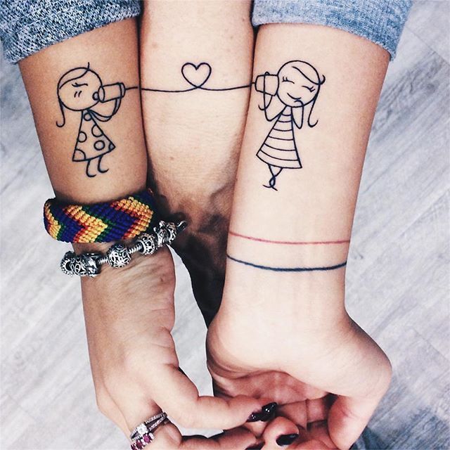 two people holding hands with tattoos on their arms