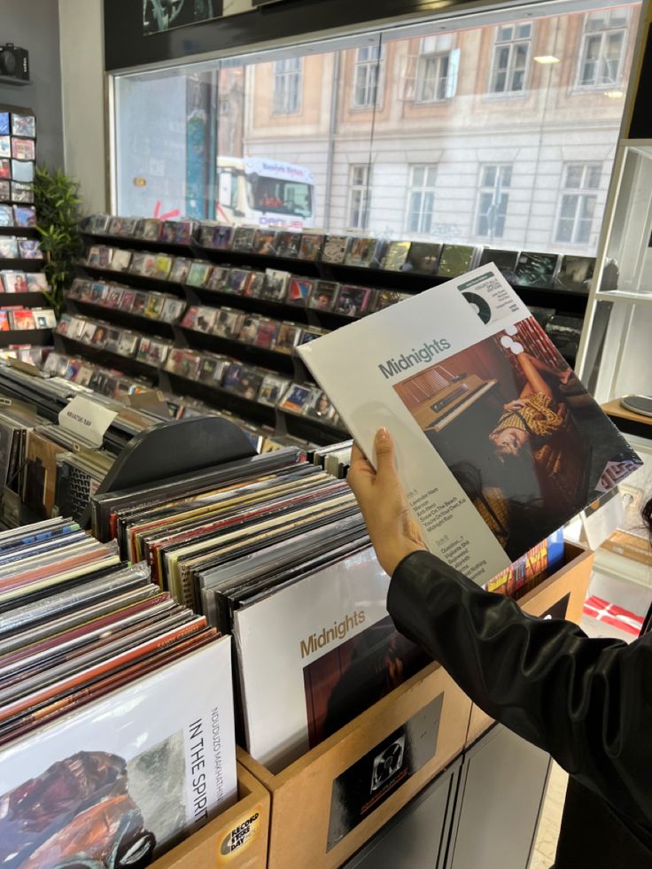 a man is looking through records in a record store with his hands on the cover