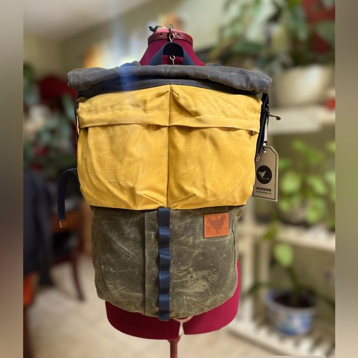 the back of a backpack on display in a room with potted plants behind it