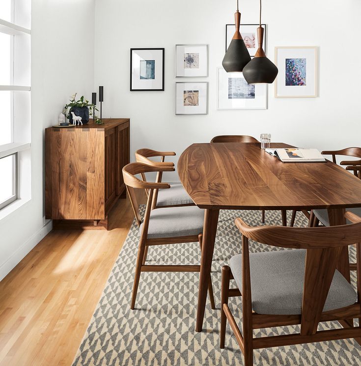 a dining room table with chairs and pictures on the wall above it, along with an area rug