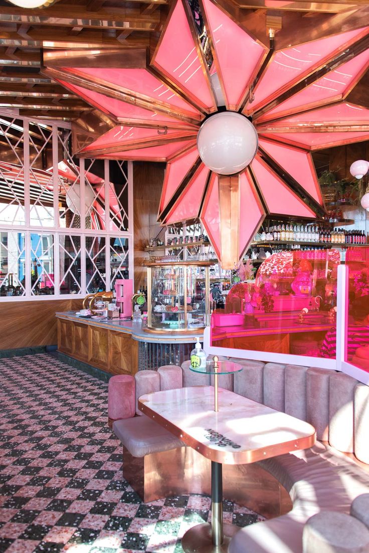 the inside of a restaurant with tables and chairs, pink umbrellas hanging from the ceiling