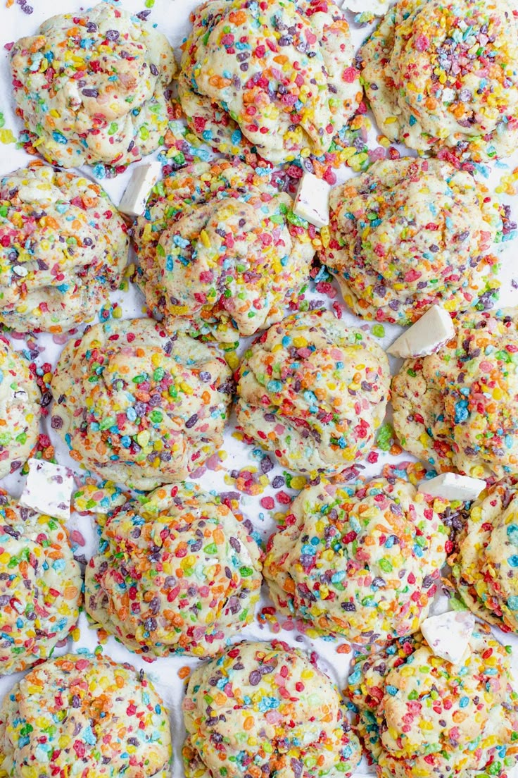 sprinkle covered cookies are sitting on a white tablecloth with colorful sprinkles