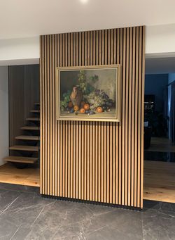 a painting on the wall next to a staircase in a room with wood paneling