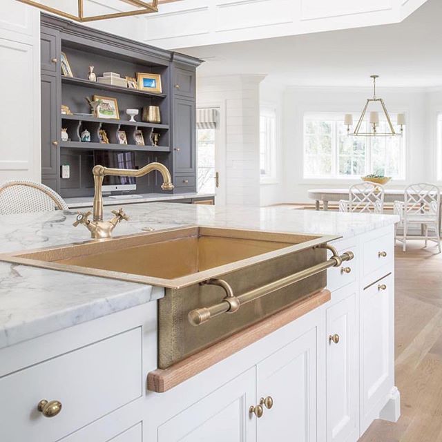 a kitchen with white cabinets and marble counter tops, gold faucet sink and open shelving