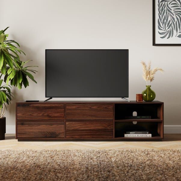 a flat screen tv sitting on top of a wooden entertainment center next to a potted plant